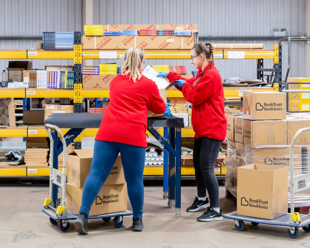 Two EC Group employees handle a pallet of BookTrust products