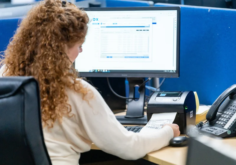 An image of the EC Group office, containing an employee preparing a delivery label