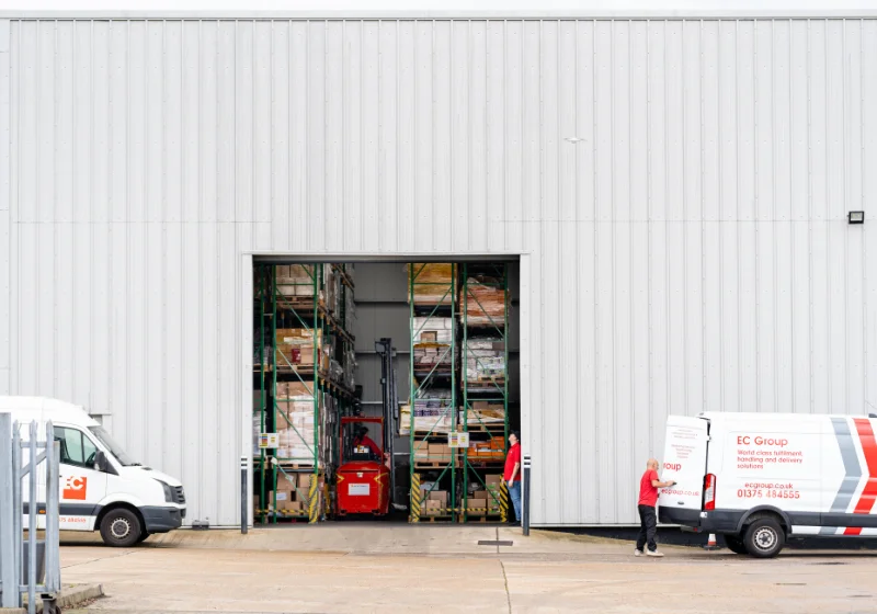 An image of EC Group's warehouse, featuring EC Group branded vans, and employees fulfilling items