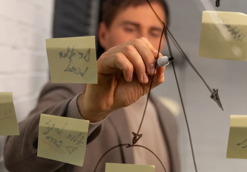 A man writing a plan on a transparent whiteboard