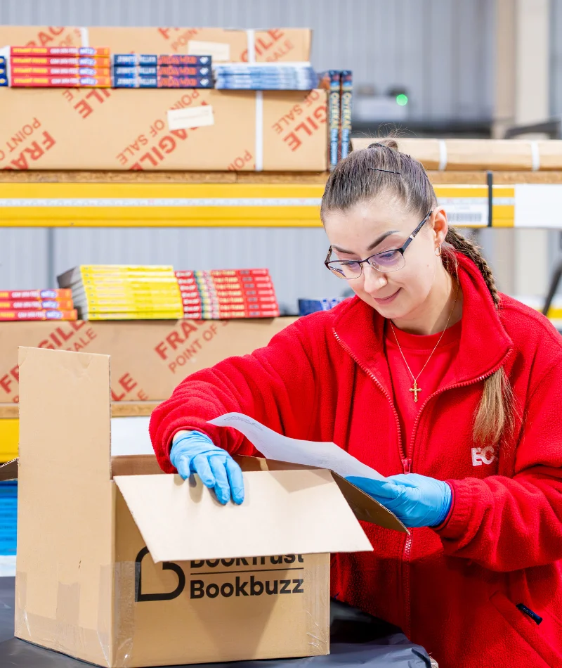 An EC Group employee consults a box of BookTrust items