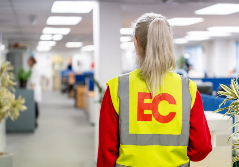 An EC Group employee walks into an office with folders and files